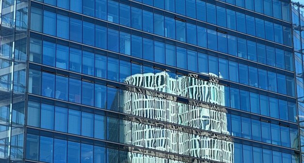 Bürohaus mit Glasfront, in der sich an anderes Gebäude spiegelt